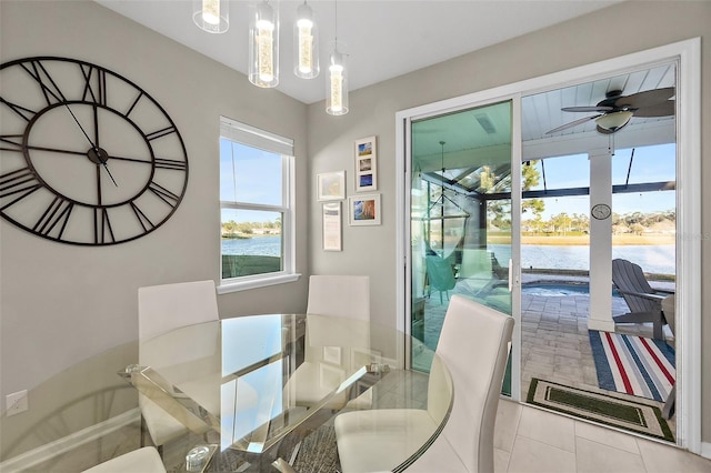 dining area featuring a sunroom, a water view, ceiling fan, and tile patterned floors