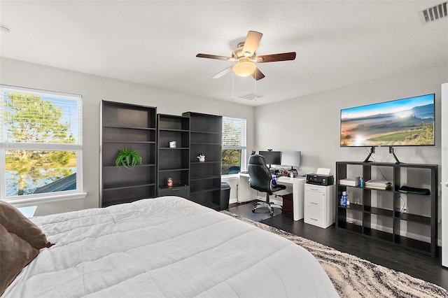 bedroom with baseboards, visible vents, dark wood finished floors, and a ceiling fan