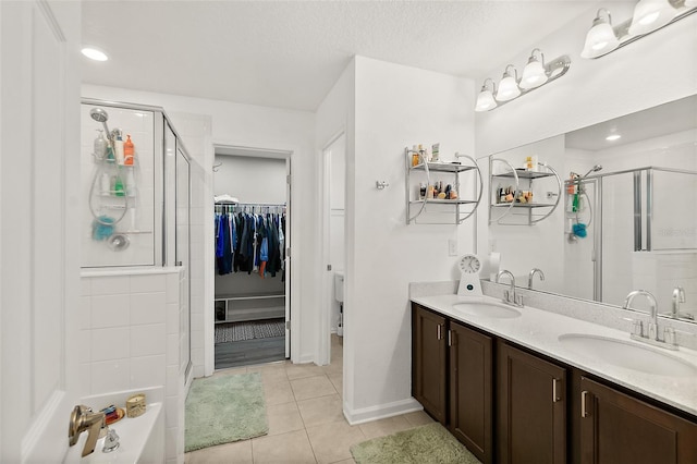 bathroom featuring tile patterned flooring, a shower stall, a spacious closet, and a sink