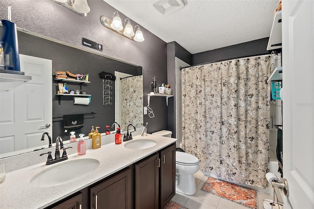 bathroom with a textured ceiling, visible vents, a sink, and tile patterned floors