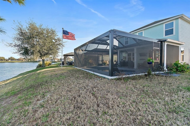 back of house featuring a water view, a lanai, a lawn, and a patio