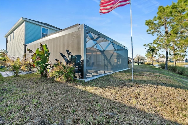 view of side of home with glass enclosure and a lawn