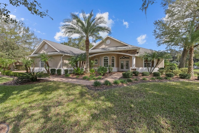 view of front facade featuring stucco siding, a front yard, and french doors