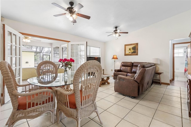 dining area featuring a ceiling fan, lofted ceiling, baseboards, and light tile patterned floors