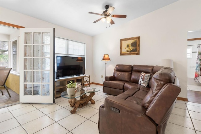 living area featuring lofted ceiling, light tile patterned floors, ceiling fan, and baseboards