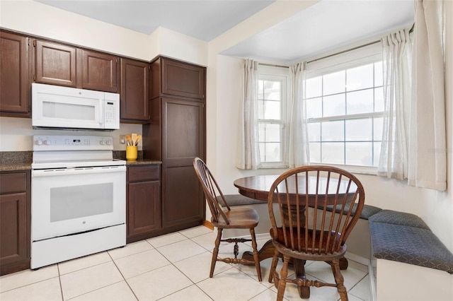 kitchen featuring light tile patterned floors, white appliances, dark countertops, and dark brown cabinetry