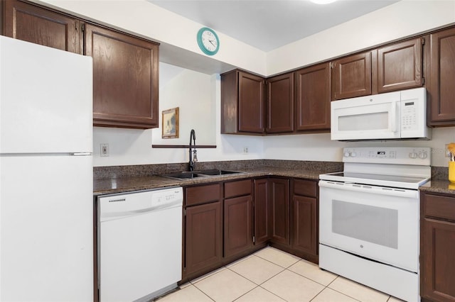 kitchen featuring dark brown cabinetry, white appliances, a sink, and light tile patterned flooring