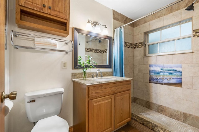 full bath featuring a tile shower, vanity, and toilet