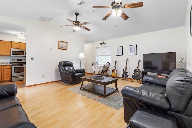 living area featuring lofted ceiling, baseboards, visible vents, and light wood-style floors