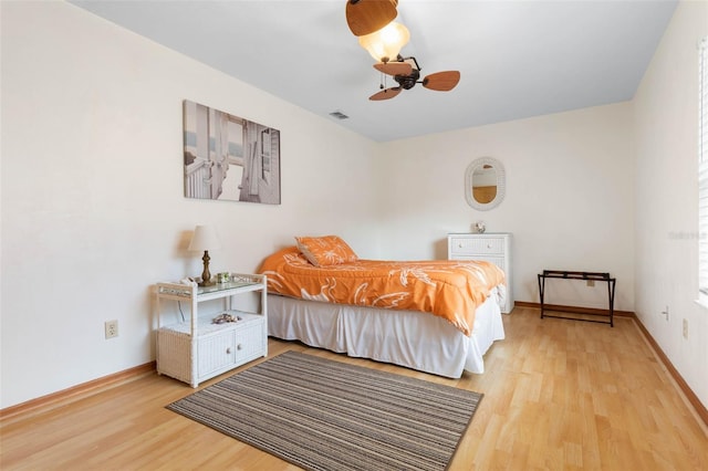 bedroom featuring light wood finished floors, baseboards, visible vents, and ceiling fan