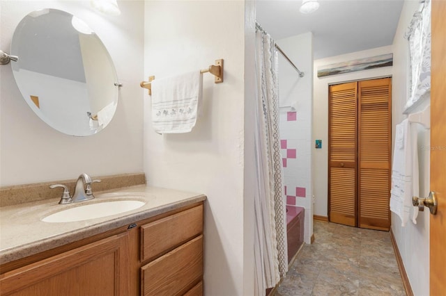 bathroom with shower / tub combo, vanity, and baseboards