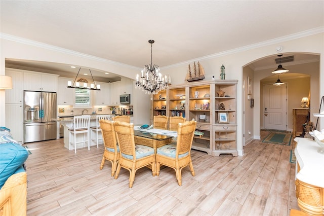 dining area with visible vents, a notable chandelier, ornamental molding, arched walkways, and light wood-style floors