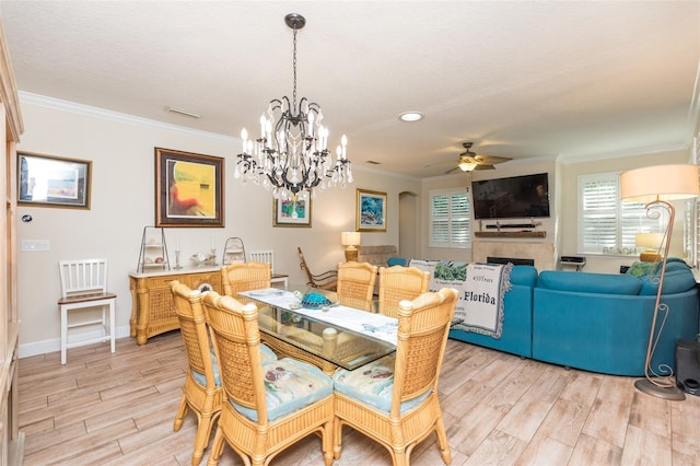 dining space with ceiling fan, a fireplace, light wood-type flooring, and ornamental molding