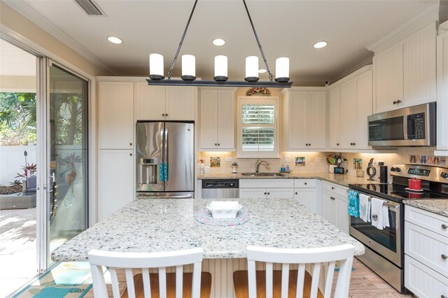 kitchen with a kitchen bar, visible vents, a sink, backsplash, and stainless steel appliances