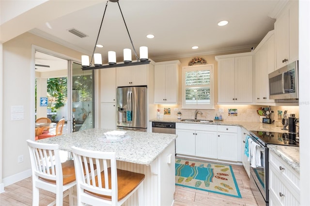 kitchen featuring tasteful backsplash, visible vents, ornamental molding, stainless steel appliances, and a sink