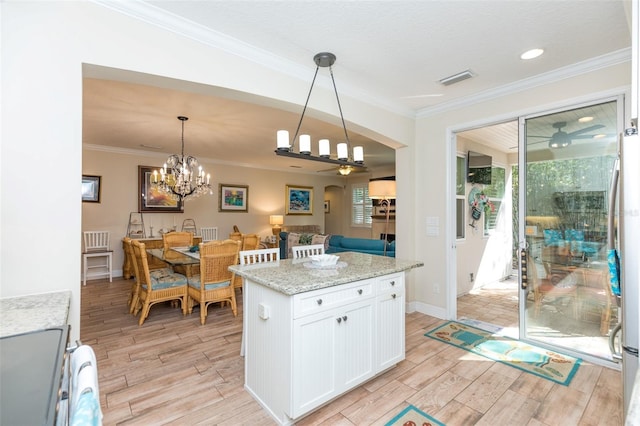 kitchen with wood finish floors, light stone counters, crown molding, and ceiling fan with notable chandelier