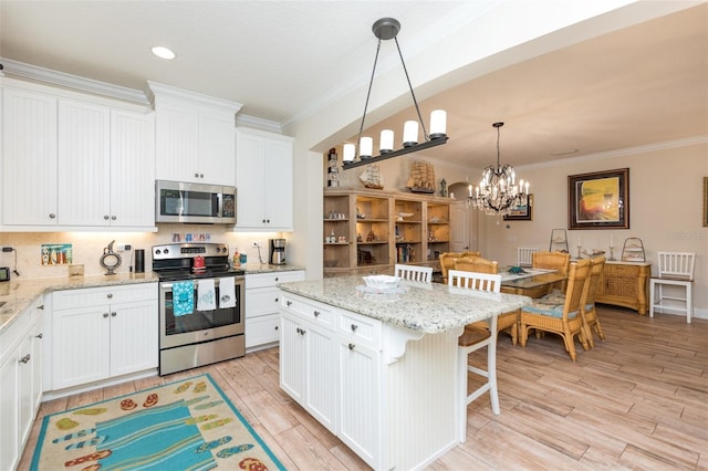 kitchen featuring stainless steel appliances, a kitchen breakfast bar, light wood-style flooring, and crown molding