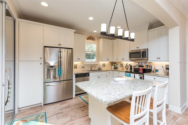 kitchen with tasteful backsplash, light wood-style flooring, appliances with stainless steel finishes, and a sink