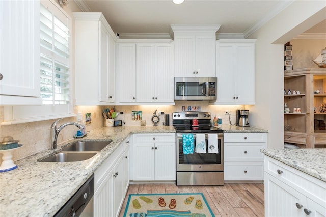 kitchen with a sink, stainless steel appliances, white cabinets, light wood-style floors, and crown molding