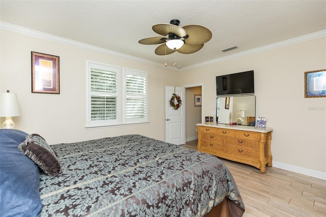 bedroom featuring visible vents, baseboards, ornamental molding, light wood-style flooring, and a ceiling fan