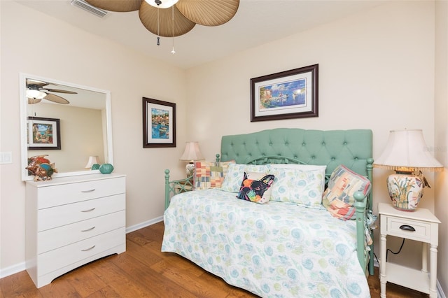 bedroom with ceiling fan, wood finished floors, visible vents, and baseboards