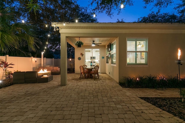 view of patio / terrace with fence, ceiling fan, outdoor dining space, and an outdoor fire pit