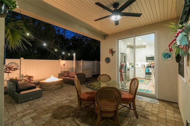 view of patio / terrace featuring a fire pit, fence, and ceiling fan