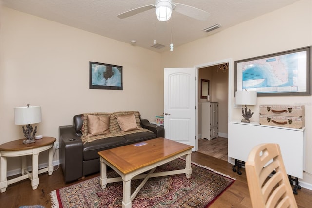 living room with visible vents, baseboards, ceiling fan, wood finished floors, and a textured ceiling