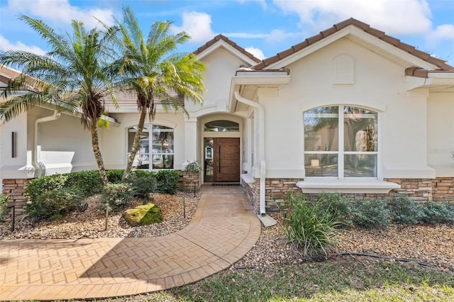 view of front of property featuring stone siding, a tiled roof, and stucco siding