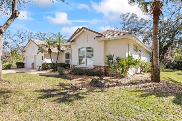 mediterranean / spanish home with concrete driveway, stone siding, an attached garage, a front lawn, and stucco siding