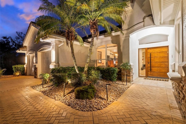 exterior entry at dusk featuring stucco siding