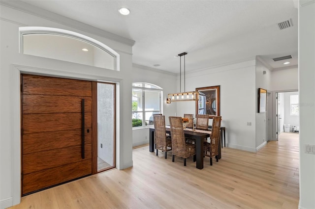 foyer entrance featuring crown molding, baseboards, visible vents, and light wood-style floors