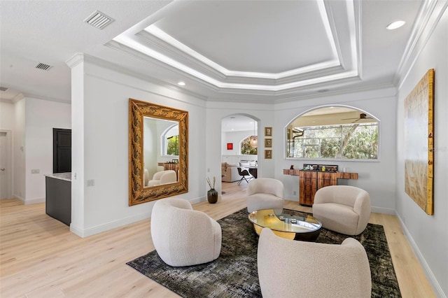 living area featuring visible vents, a raised ceiling, and arched walkways