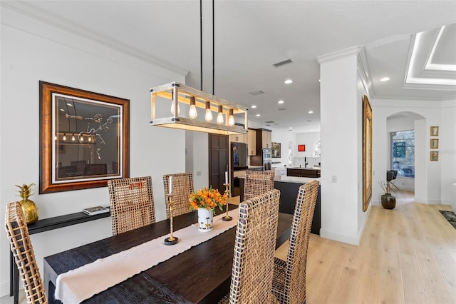 dining space featuring arched walkways, light wood finished floors, recessed lighting, visible vents, and ornamental molding