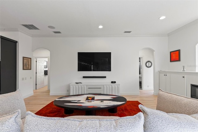 living room featuring arched walkways, visible vents, crown molding, and wood finished floors