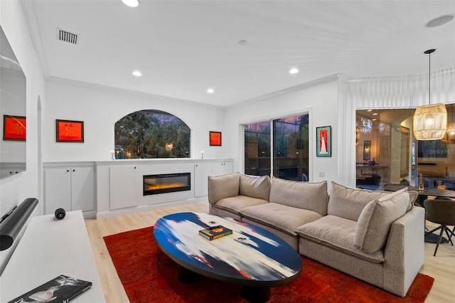 living area with a glass covered fireplace, visible vents, recessed lighting, and wood finished floors