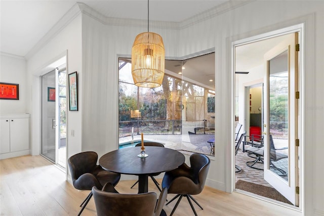 dining room with a notable chandelier, crown molding, and wood finished floors