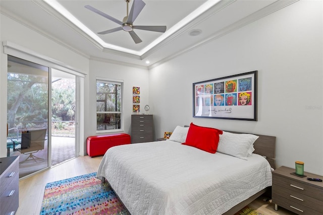 bedroom featuring hardwood / wood-style flooring, a ceiling fan, access to exterior, ornamental molding, and a raised ceiling