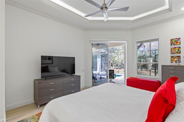 bedroom featuring access to exterior, a tray ceiling, ornamental molding, wood finished floors, and baseboards