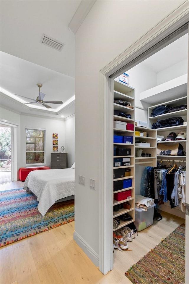 bedroom featuring wood finished floors, visible vents, baseboards, a closet, and a tray ceiling