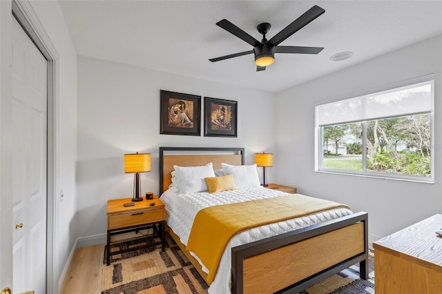 bedroom featuring light wood-style floors, a closet, baseboards, and a ceiling fan