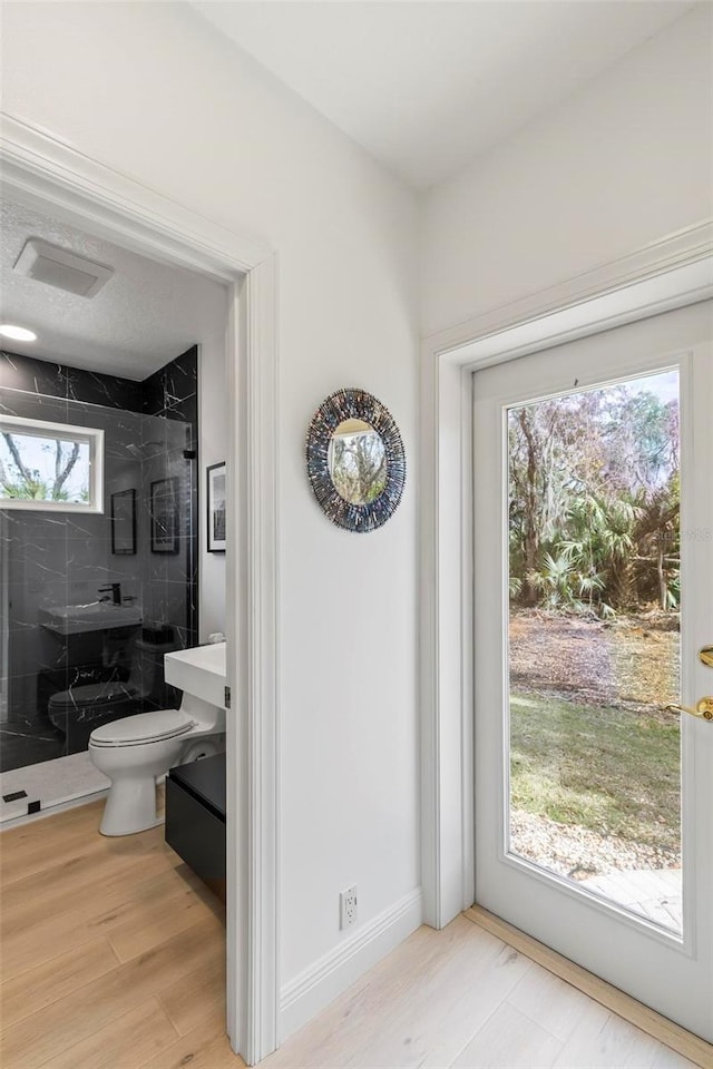 bathroom with toilet, wood finished floors, visible vents, baseboards, and a stall shower