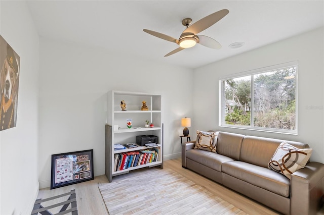 living area with light wood finished floors, baseboards, and a ceiling fan