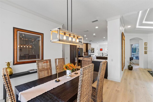 dining space with visible vents, crown molding, recessed lighting, light wood-style floors, and arched walkways