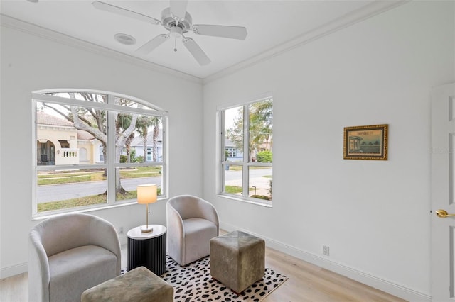 sitting room featuring crown molding, baseboards, light wood finished floors, and ceiling fan