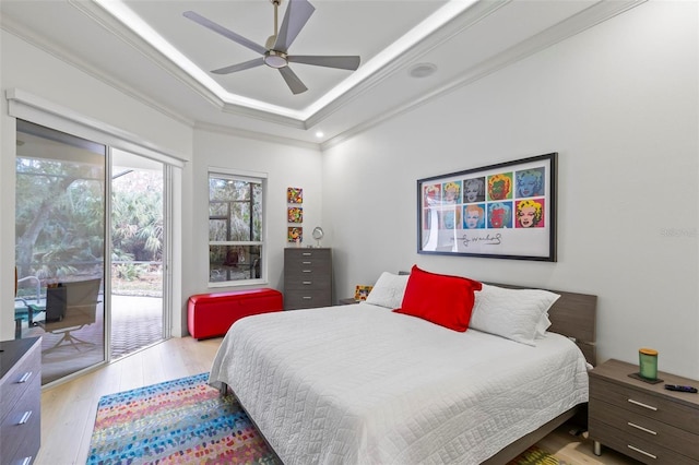 bedroom with access to exterior, crown molding, ceiling fan, hardwood / wood-style floors, and a raised ceiling