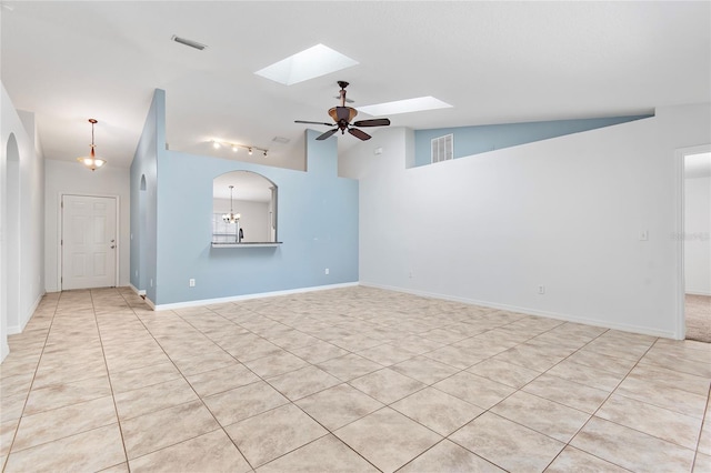 empty room featuring baseboards, lofted ceiling with skylight, visible vents, and a ceiling fan