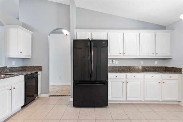 kitchen featuring lofted ceiling, black appliances, dark stone counters, and white cabinets