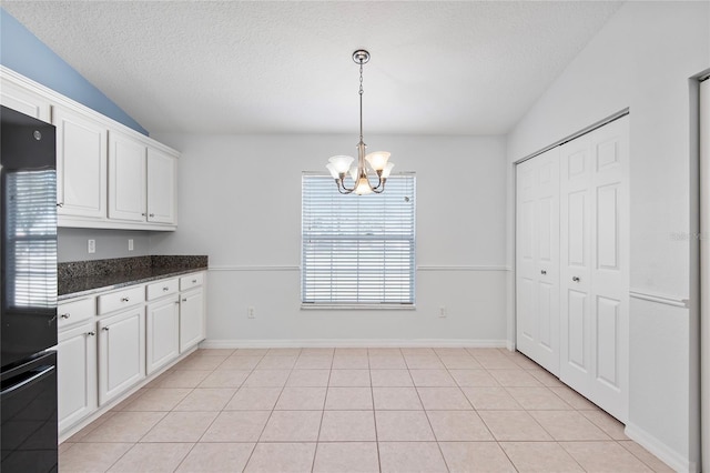 kitchen featuring dark countertops, freestanding refrigerator, white cabinets, a textured ceiling, and a chandelier