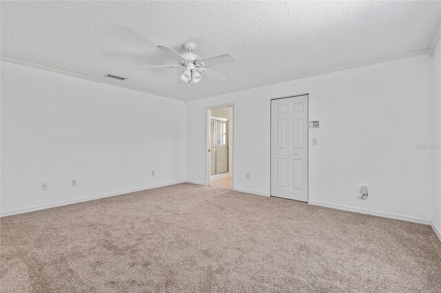 unfurnished bedroom featuring a textured ceiling, light carpet, a ceiling fan, baseboards, and crown molding